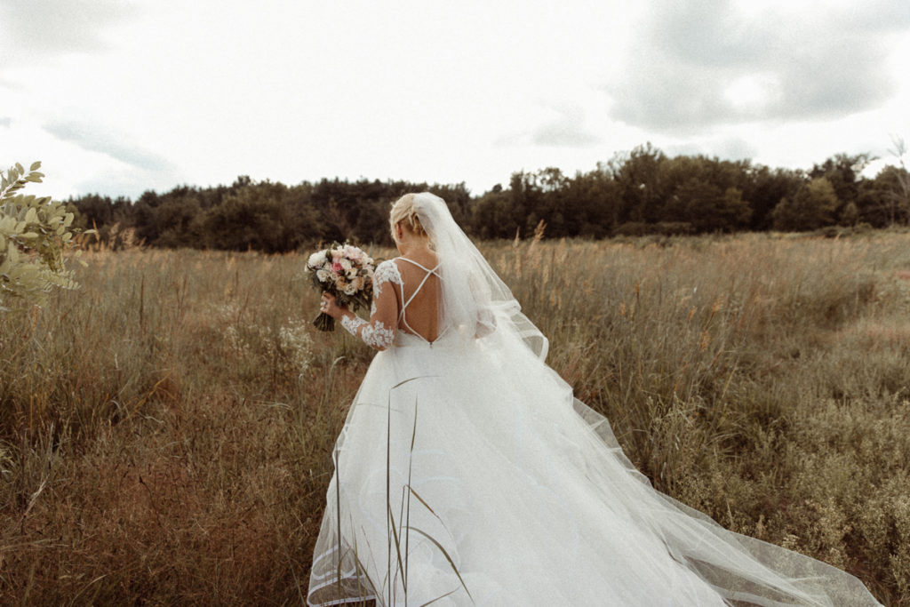 bride walking through a field in her wedding dress
