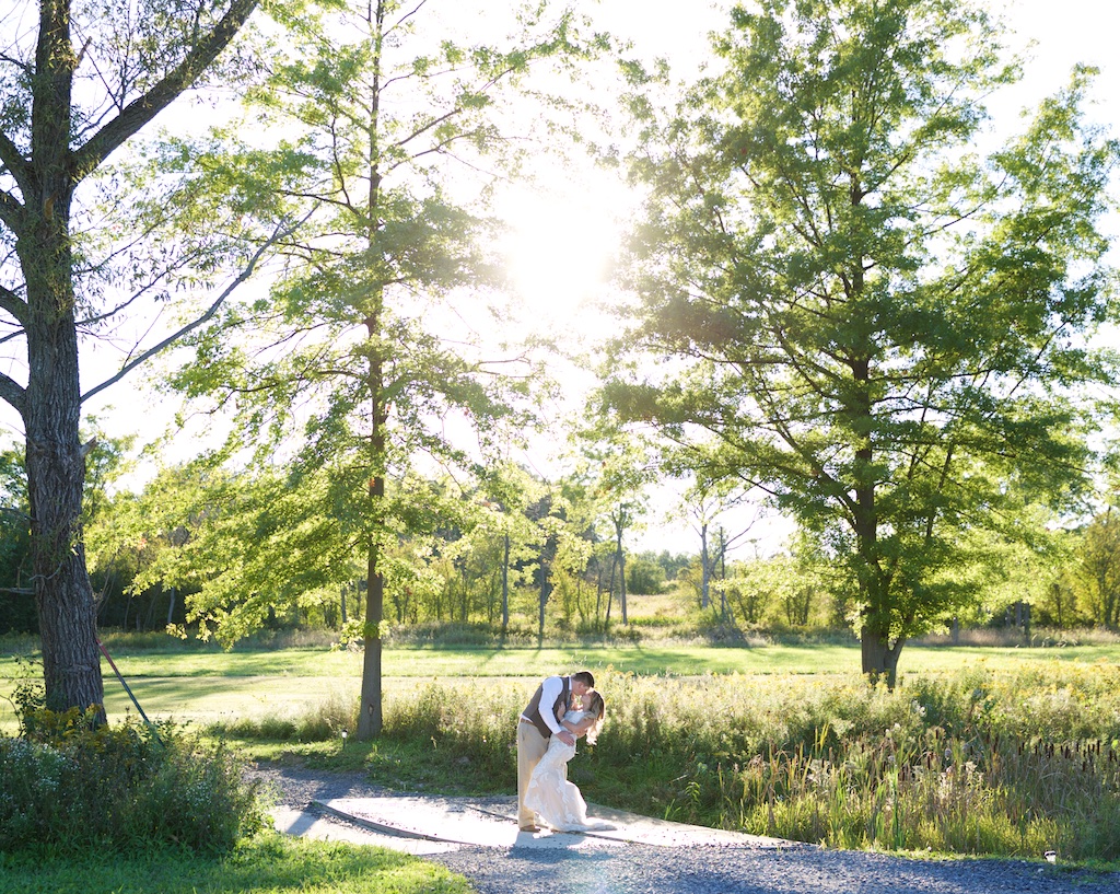 groom dips bride on bride through trees at Chantelle Marie Lakehouse Wedding