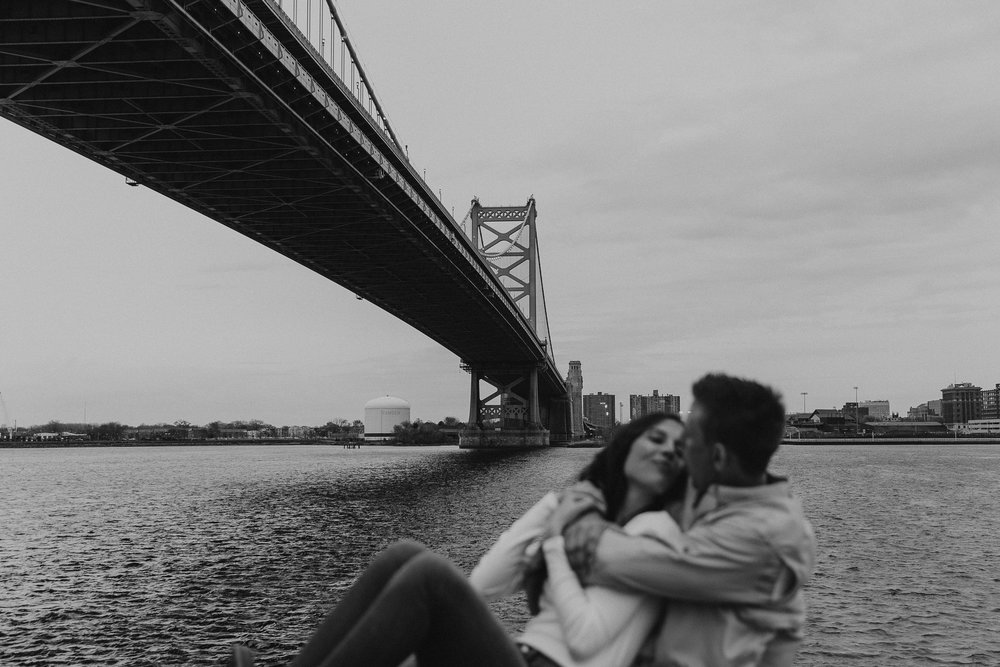 couple kisses on the Philly waterfront under the bridge