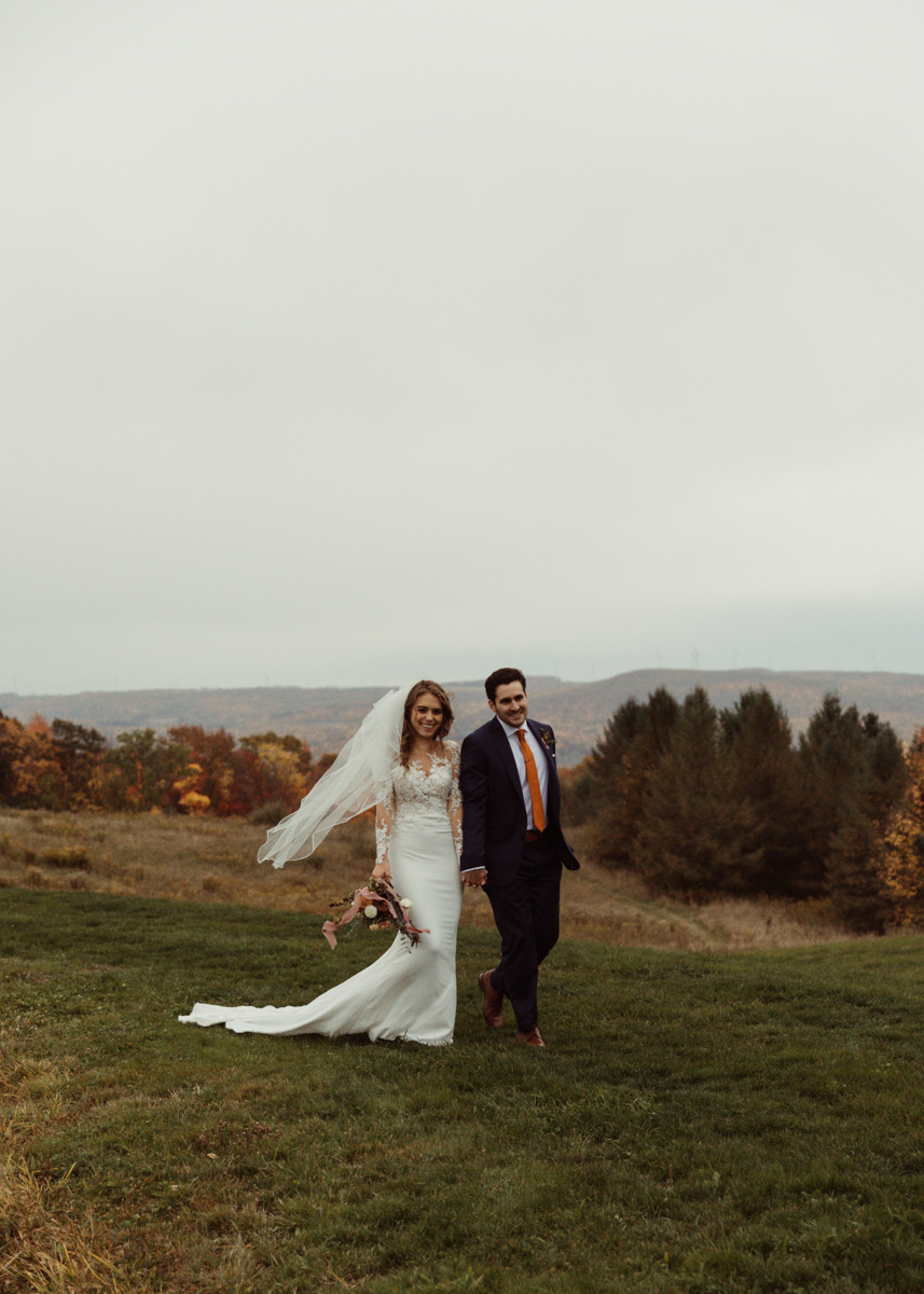 A couple is holding hands, walking at the Wren's Roost wedding venue in the Finger Lakes.