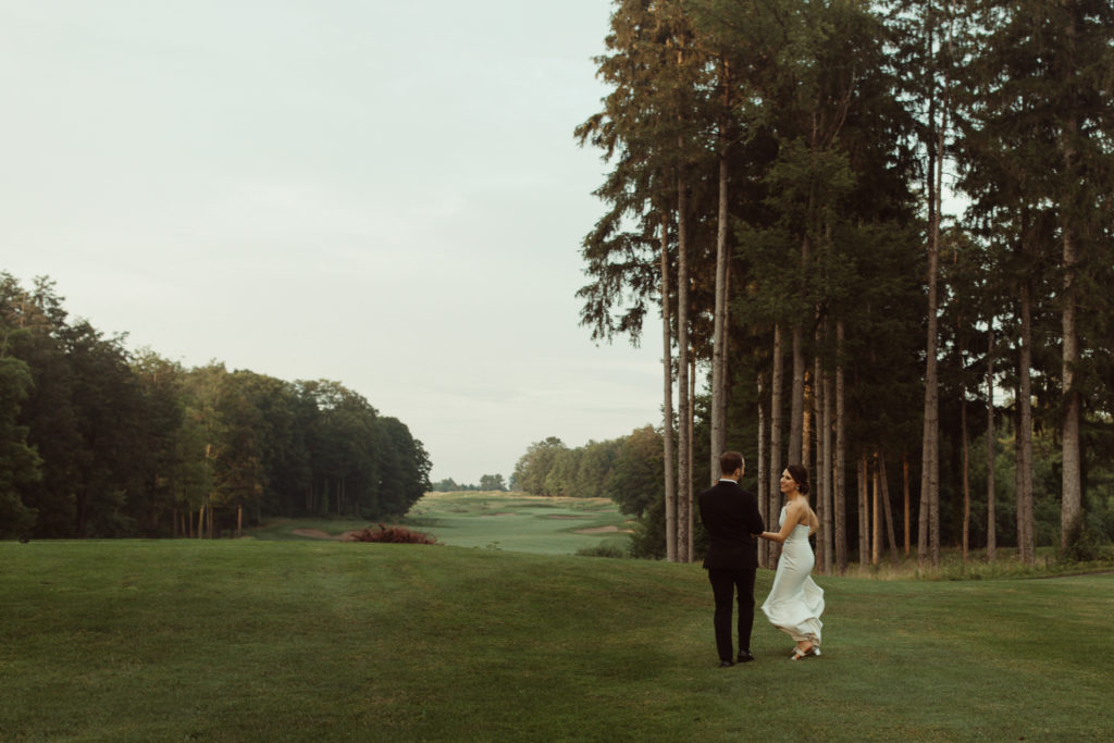 A bride and groom walk on the golf course outside of Shenandoah Ballroom, at Turningstone Resort and Casino.