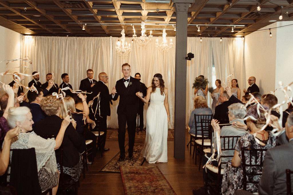 A couple walking down the aisle at their ceremony at the SKY Armory, one of the best wedding venues in Syracuse.