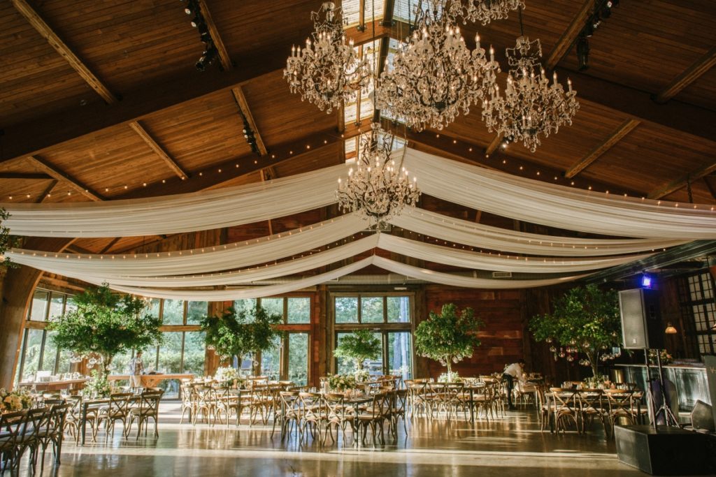 A high-end wedding venue reception with chandeliers, draping and elevated florals in the Catskills of NY.