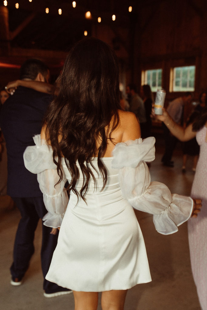 A bride walks away in a second mini dress for her reception. A fun way to make your day more unique is outfit changes.