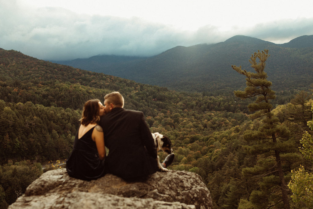 Married couple sitting on rock cliff in the Adirondacks. I picturesque place to have your wedding in New York state.