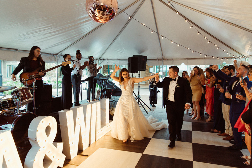 A wedding made unique in the choice of band, light-up letters and decor, as the bride and groom walk into their reception.